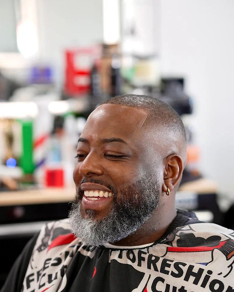A client smiling in the ProFRESHional Cuts cape