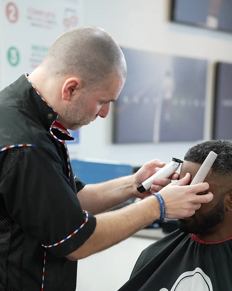 A barber working on a fade at a station